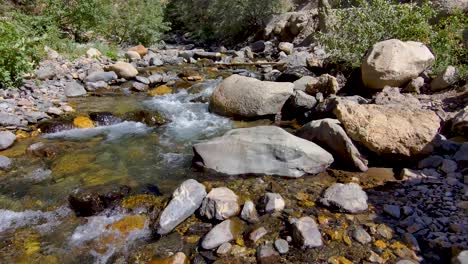 pull back view of a shallow mountain creek in a rocky canyon - aerial view slow motion