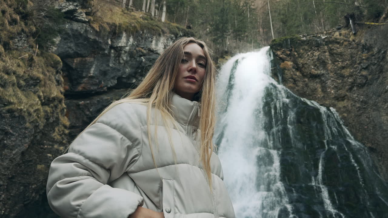 Woman standing in front of a waterfall in a forest