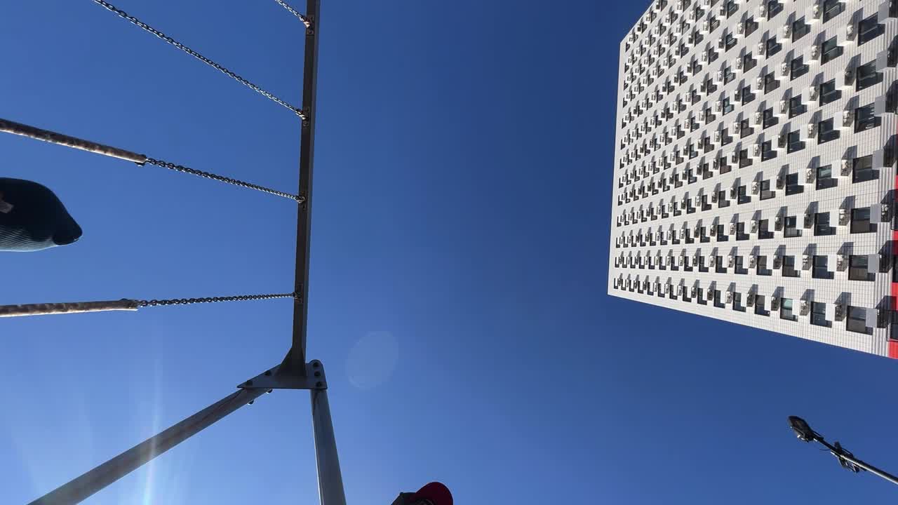 Child on a swing with building and blue sky