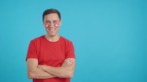 Man standing with swiss flag painted on face smiling