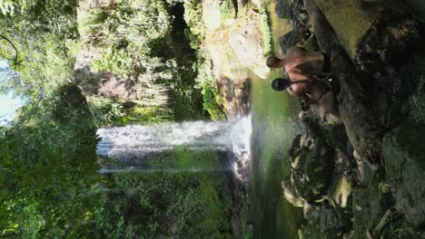 vertical flyover tourist couple at jungle waterfall in amboro, bolivia