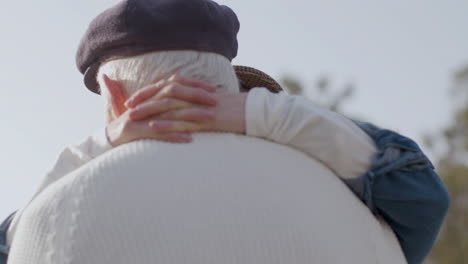 close up shot of loving elderly couple dancing outdoors and kissing in city park