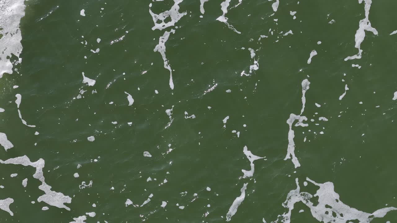 Green river water surface with foamy waves, bubbles, and gentle movement in natural daylight