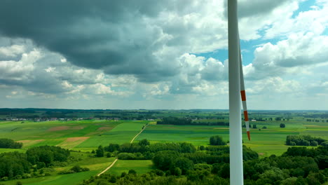 imágenes aéreas con una turbina eólica en un telón de fondo de campos verdes y un pueblo en la distancia