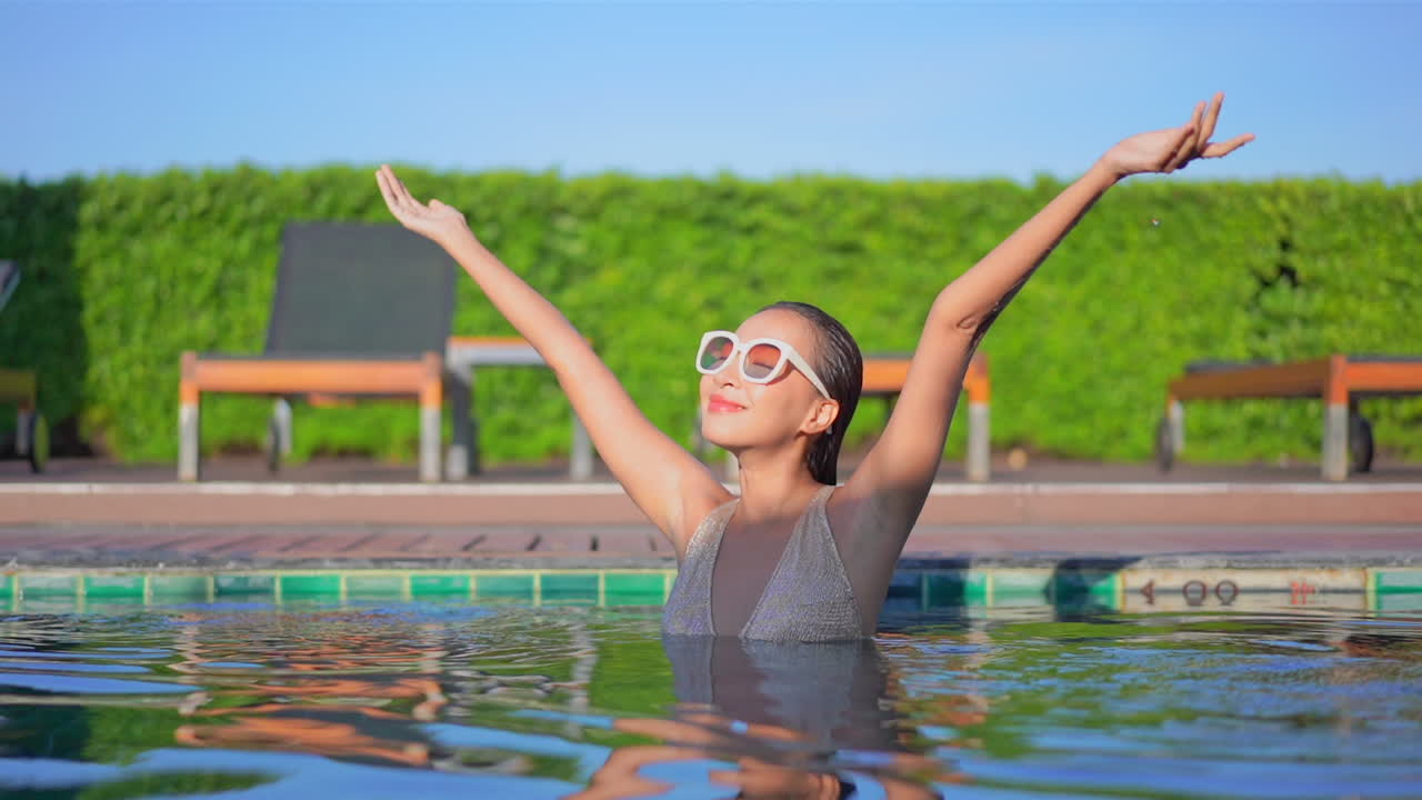 una mujer joven en una piscina levanta los brazos con felicidad