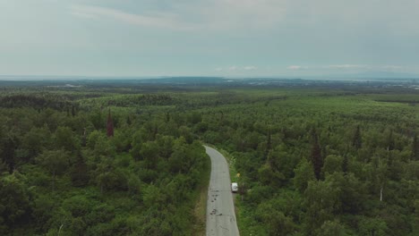 volando sobre una carretera remota en medio de extensos bosques cerca de anchorage, alaska