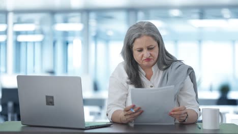 tensa y estresada directora india senior leyendo informes de negocios