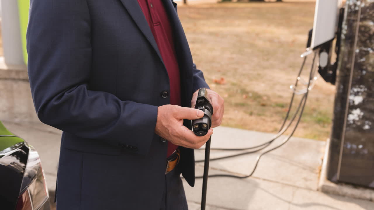 전기 자동차를 충전하는 백인 남자의 중간 섹션