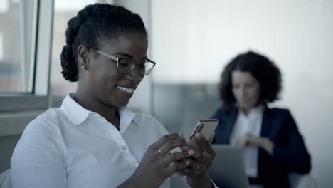 smiling african american woman using smartphone