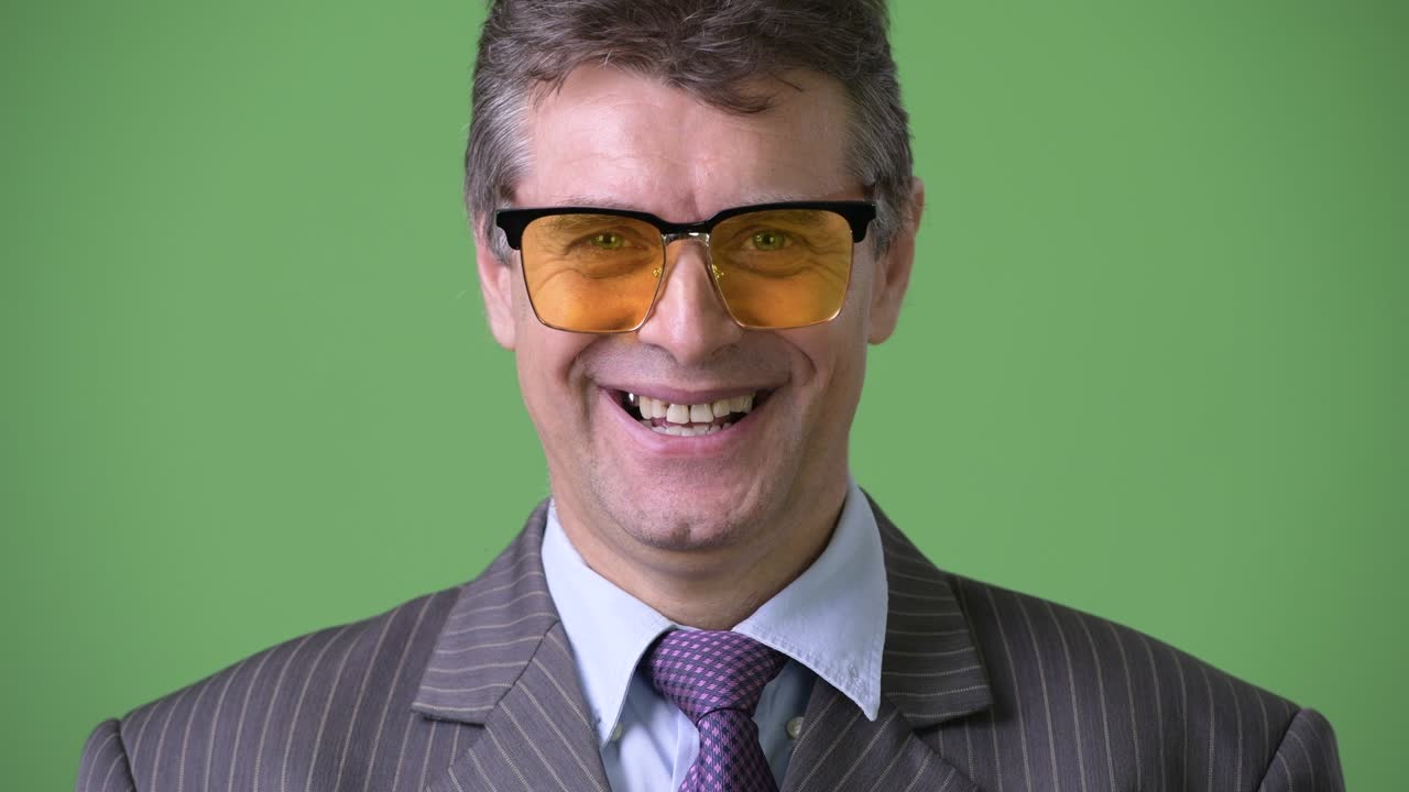 hombre de negocios maduro y guapo contra un fondo verde