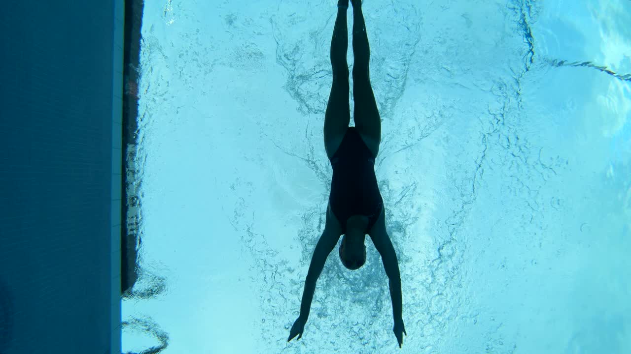 Underwater shot of a female swimmer swimming speedily through a pool