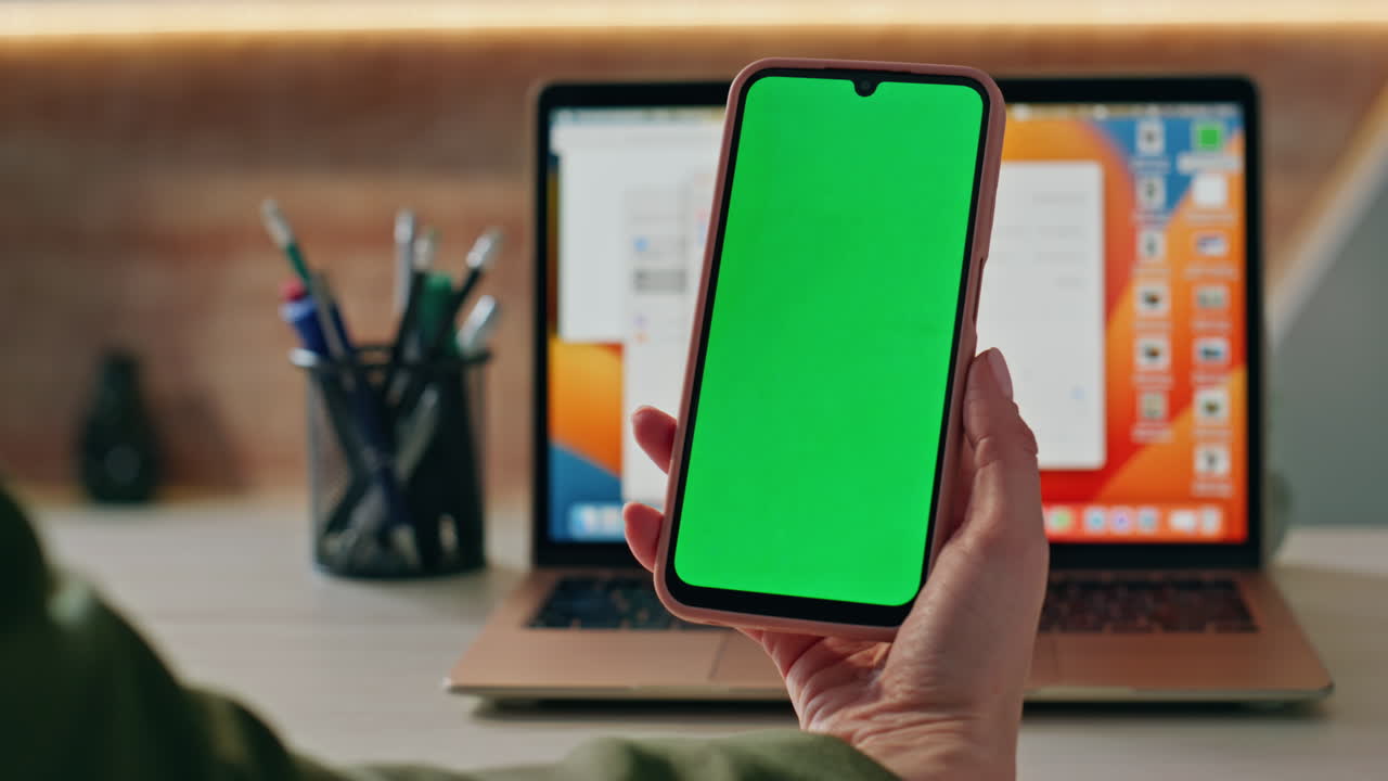 Woman hands browsing greenscreen smartphone application at work desk close up.