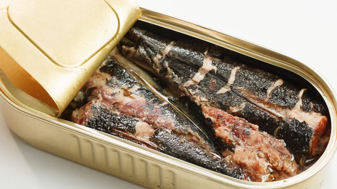 Opening sardine fish or tuna can, man open the canned anchovy on the table. Close up on professional kitchen.