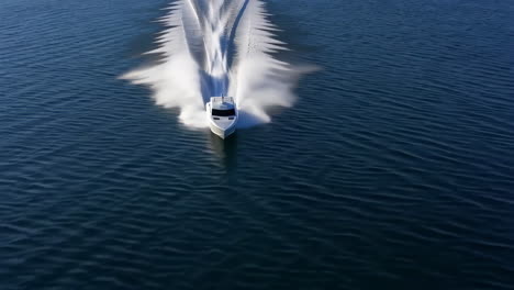 a high-speed motorboat creates a large wake on dark blue water