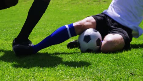 two football players striking a ball in the field