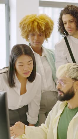 coworkers talking while looking at a one computer screen