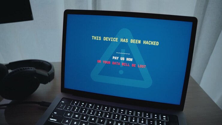 Hacker che prende il controllo di un laptop che mostra un messaggio di riscatto che richiede il pagamento per sbloccare dati e informazioni personali e privati. Minaccia di attività di cybercrimine e rischio per la sicurezza in caso di violazione