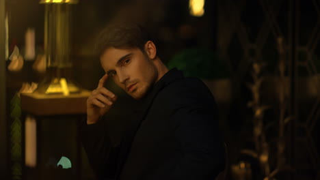 pensive boss sitting in dark room. young man touching face in blurred background