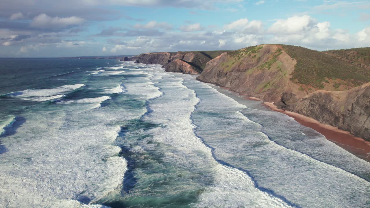 Aerial 4k drone establishing shot of heavy waves at praia da Cordoama hidden cliff coastline near the Algarve region of Portugal