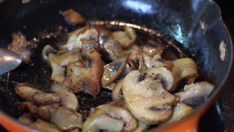 sliced mushrooms are frying in a hot red pan