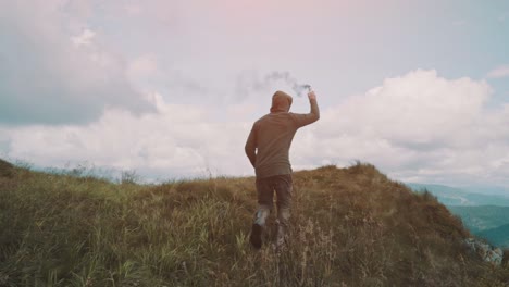 the man running on the mountain with a smoke bomb. slow motion