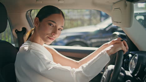 chic model posing car holding hands on wheel close up. woman sitting in vehicle