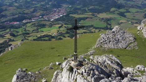 aerial drone view of a large iron cross on top of a mountain in the basque country