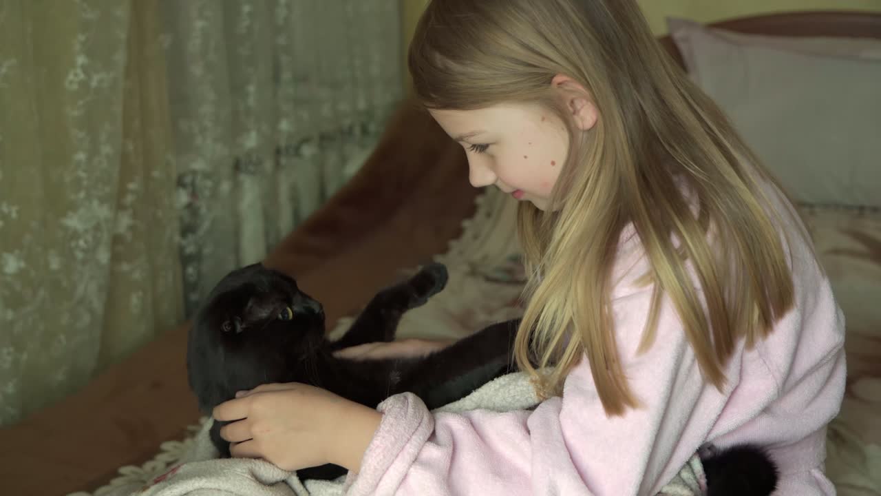 어린 소녀가 애완동물 고양이와 놀고 있다.