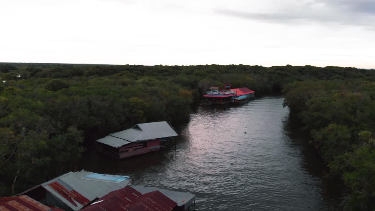 An aerial drone shot over a partially submerged forest in Cambodia, with small boats navigating through the trees, showcasing the region's unique seasonal flooding and natural beauty.