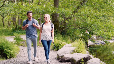 slow motion shot of young couple hiking along path by river in uk lake district