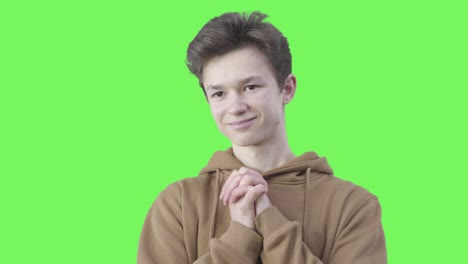 portrait of caucasian boy showing pleasure at green screen background. teenager expressing affection and smiling. chromakey.