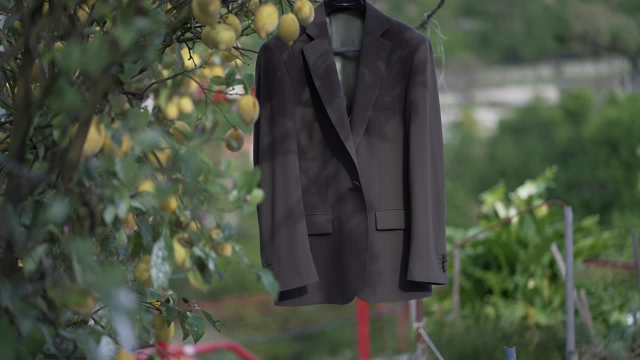 Dark suit jacket hanging among fruit trees outdoors