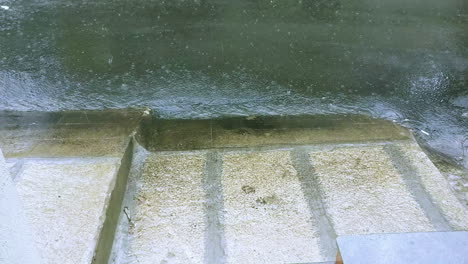 pequeña corriente de agua que fluye por el orificio de drenaje durante las fuertes lluvias