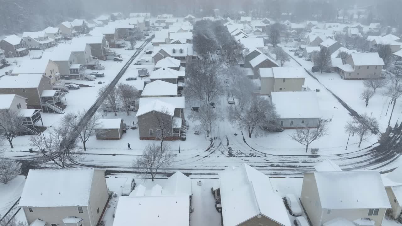 冬の雪の中、アメリカの近所の雪の歩道を歩く歩行者。空撮による横からのワイドショット。12月の大雪。ペンシルベニア州の静かな郊外でのクリスマス時期。