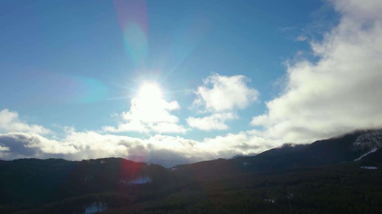 Nature captured with a drone with the landscape, mountains covered in snow at golden hour at sunrise with  forest and surrounding hills captured in Slovenia above forest Pokljuka  above a village