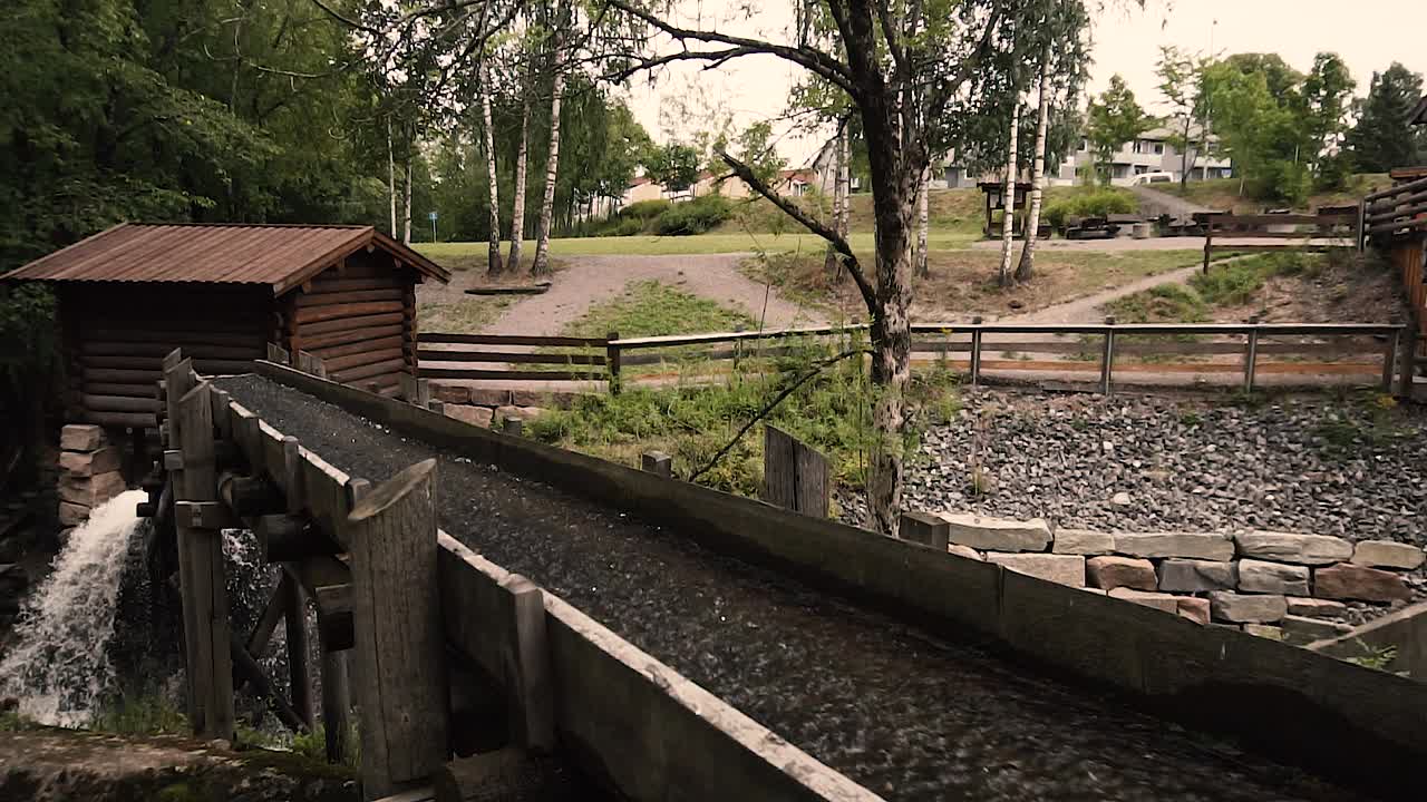 agua pasando por el antiguo molino de río de madera en cámara lenta