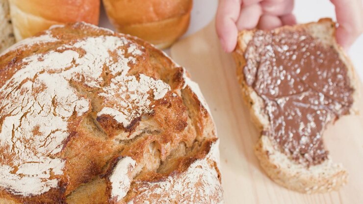 Close-up shot of hands lifting a slice of bread topped with chocolate hazelnut cream.