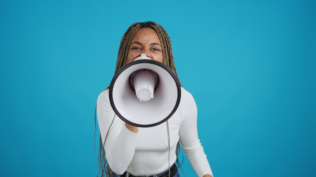Young Black Woman Shouting into Megaphone Against Blue Background