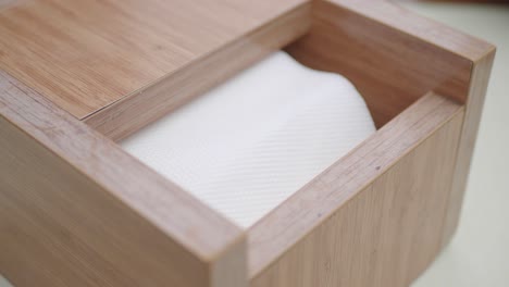 person taking tissue from a wooden tissue box