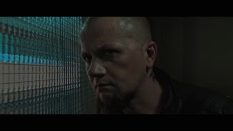 a bald dangerous looking man checks the corridor through reinforced glass