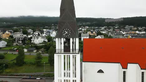 large-church-tower-with-bell-and-red-roof-in-a-small-town,-norway,-europe,-drone