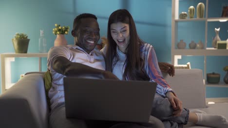 una feliz pareja casada viendo una película en su casa por la noche.