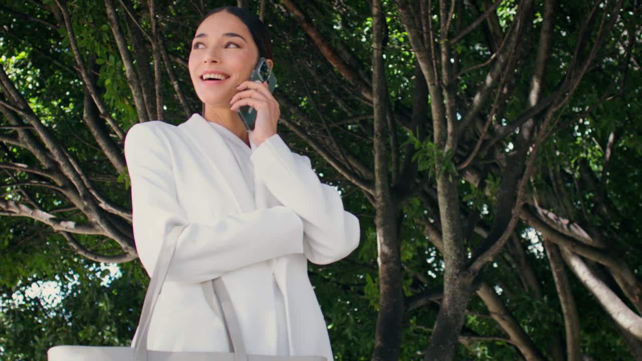 행복한 사업가 여성이 나무 에 서서 전화를 하고 있습니다. 부인 전화