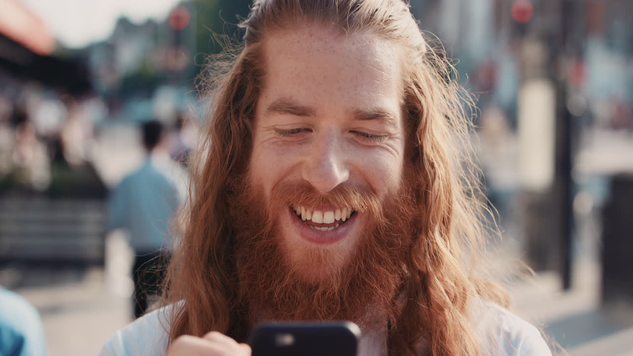 Ritratto in slow motion di un uomo hipster felice con la barba che usa lo smartphone