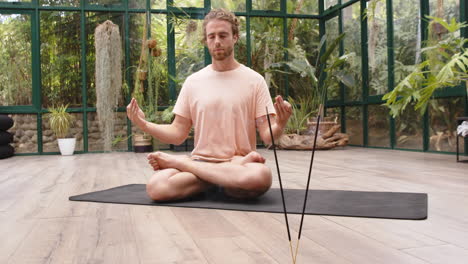 meditating on yoga mat, man practicing mindfulness in glass house