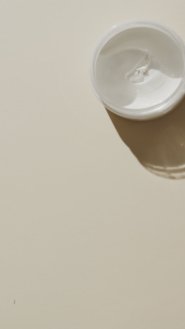 Vertical video of close up of cream tub on white background