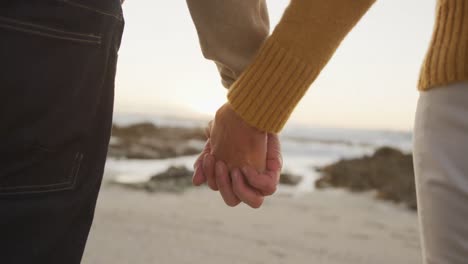 close up view of senior couple holding hands at beach