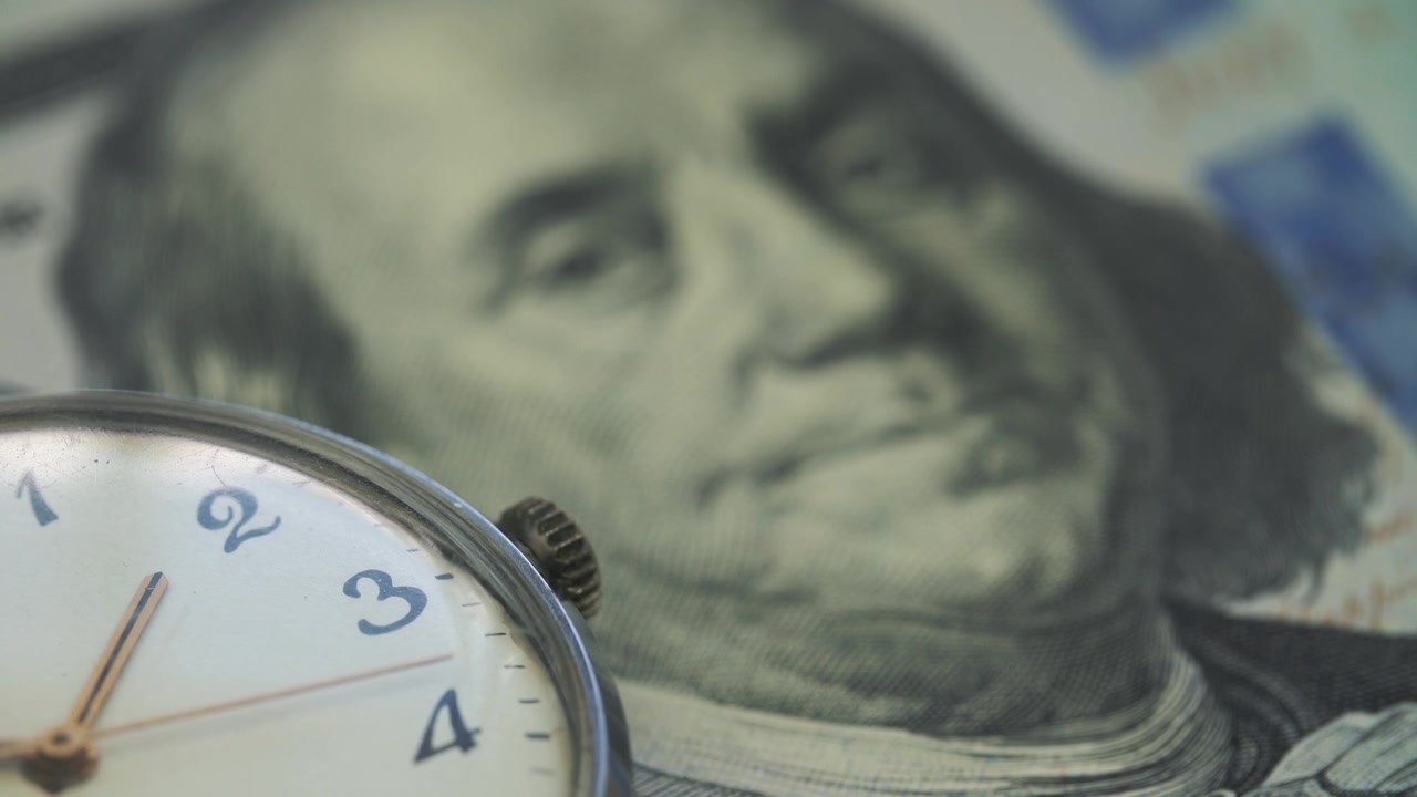 Primer plano de reloj vintage en funcionamiento con billete de 100 dólares estadounidenses