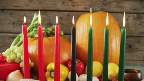 Composition-of-seven-lit-candles-and-halloween-pumpkins-and-vegetables