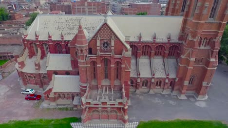 a beautiful old church aerial view, a black kite sat at the cross of the church, the church with red bricks and two cars parked at the corner